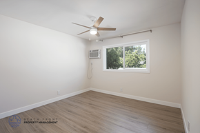 Long Beach apartment for rent - A room with a ceiling fan and a window showing trees outside.