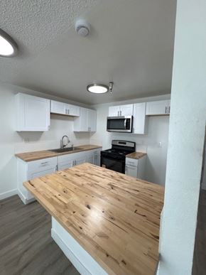 Santa Ana apartment for rent - A kitchen with a wooden counter top and white cabinets.
