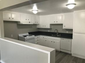 San Pedro apartment for rent - A kitchen with white cabinets and a black countertop.