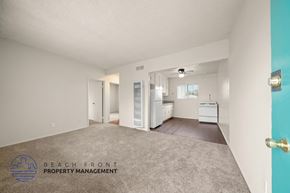 Wilmington apartment for rent - A spacious empty room with a kitchen area in the background.