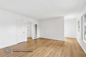 Hawthorne apartment for rent - A spacious room with wooden flooring and white walls, with a door on the left and a window on the right.