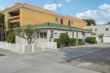 Long Beach apartment for rent - A white picket fence in front of a yellow building.