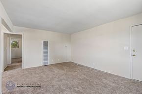 Inglewood apartment for rent - A spacious room with a carpeted floor and a door on the right side.