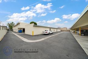 Hawthorne apartment for rent - A parking lot with a white car parked in front of a building with the words Beach Front Property Management.