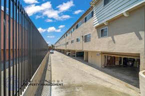 Inglewood apartment for rent - A view of a street with buildings on both sides and a fence on the left.