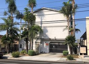 Long Beach apartment for rent - a white building with a gate and palm trees