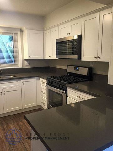 Laguna Beach apartment for rent - A kitchen with white cabinets and a black stove top oven.