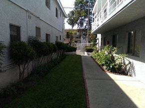 Wilmington apartment for rent - A long, narrow walkway between two buildings with green grass on either side.