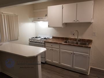Signal Hill apartment for rent - a kitchen with white cabinets and a sink and a stove