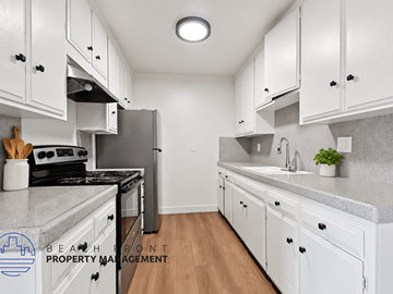 Santa Ana apartment for rent - A kitchen with white cabinets and a Beafront Property Management logo.