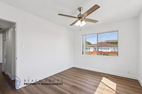 San Pedro apartment for rent - A room with a ceiling fan and a window showing a view of a building.