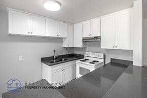 Long Beach apartment for rent - A kitchen with white cabinets and a stove top oven.