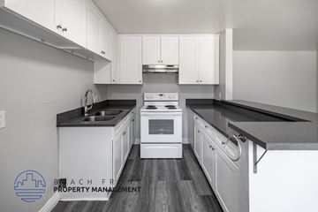 Long Beach apartment for rent - A kitchen with white cabinets and black countertops.