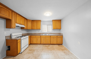 Long Beach apartment for rent - A kitchen with wooden cabinets and a white stove top oven.