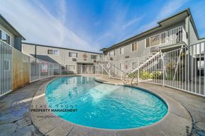 Downey apartment for rent - A pool in a courtyard surrounded by a fence and buildings.