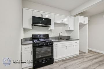 Long Beach apartment for rent - A kitchen with white cabinets and a black stove top oven.