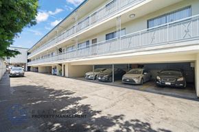 Hawthorne apartment for rent - A parking lot with cars parked in front of a building with a balcony.