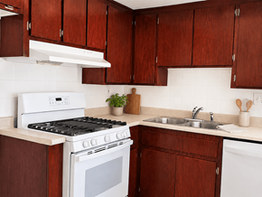 Huntington Beach apartment for rent - A white stove and sink in a kitchen with brown cabinets.