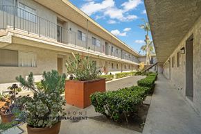 Gardena apartment for rent - A courtyard with a brick planter and a sign that says Front Management.