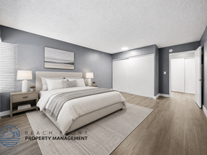 Santa Ana apartment for rent - A well-lit bedroom with a large bed and a nightstand with a lamp.