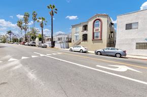 Long Beach apartment for rent - A street with cars parked on the side and a building with a red window.