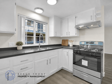 Long Beach apartment for rent - A kitchen with white cabinets and a stove top oven.