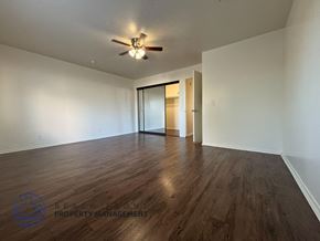 Hawthorne apartment for rent - A spacious room with wooden floors and a ceiling fan.