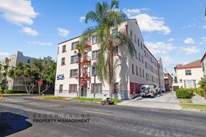 Los Angeles apartment for rent - a large white building with palm trees in front of it on a street