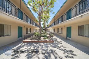 Paramount apartment for rent - A courtyard with a tree and a fence in the middle of a building complex.