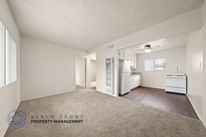 Wilmington apartment for rent - A spacious empty room with a carpeted floor and a logo for Beach Front Property Management in the bottom left corner.