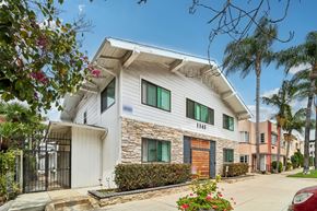 Long Beach apartment for rent - A white house with a black gate and a red car parked in front.
