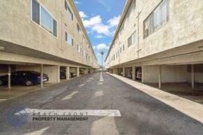 Gardena apartment for rent - A long, empty parking garage with a logo for Beach Front Property Management in the bottom left corner.