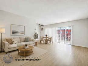 Inglewood apartment for rent - A living room with a couch, a coffee table, a painting, a plant, and a sliding glass door leading to a balcony.