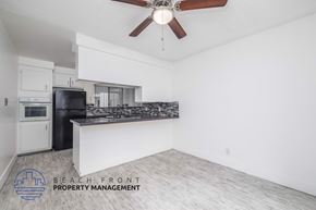 Long Beach apartment for rent - A room with a ceiling fan and a logo for Beach Front Property Management.