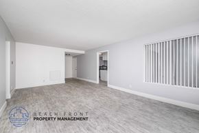 Long Beach apartment for rent - A spacious room with a logo for Beach Front Property Management on the floor.