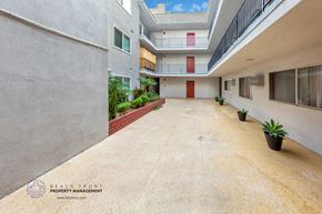 Los Angeles apartment for rent - A courtyard with a red door and a balcony.