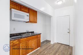 Los Angeles apartment for rent - A kitchen with wooden cabinets and a white microwave above the sink.