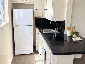 Los Angeles apartment for rent - A white refrigerator is in a kitchen with black countertops.