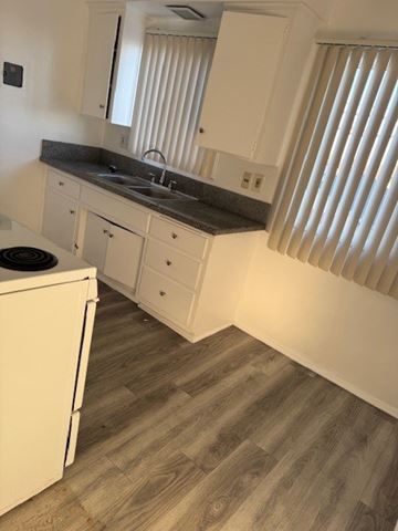 Gardena apartment for rent - A kitchen with white cabinets and a black stove top oven.