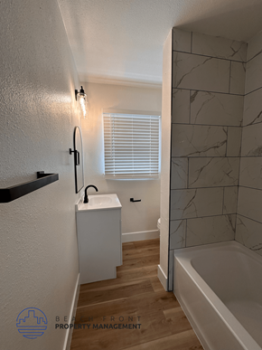 Santa Ana apartment for rent - A bathroom with a white tub, sink, and a window with blinds.