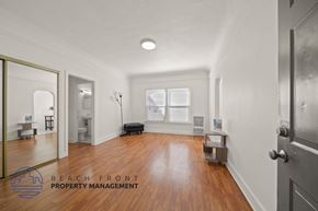 Los Angeles apartment for rent - A spacious room with wooden floors and a large mirror on the wall.