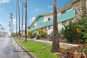 Los Angeles apartment for rent - A street view with a building and palm trees.