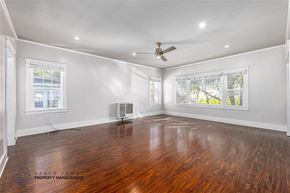 Long Beach apartment for rent - A spacious room with wooden floors and a ceiling fan.
