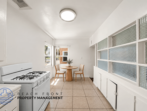Los Angeles apartment for rent - A kitchen with a stove top oven and a dining table with chairs.