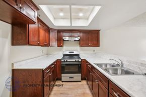 Santa Ana apartment for rent - A kitchen with wooden cabinets and a stove top oven.