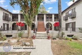 Riverside apartment for rent - A courtyard with a staircase and a tree in front of a building with balconies.