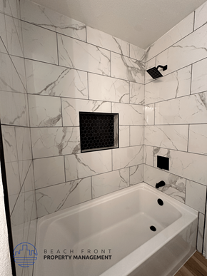 Santa Ana apartment for rent - A bathroom with a marble tile wall and a white bathtub.