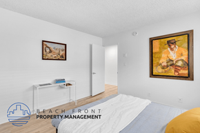 Long Beach apartment for rent - A bedroom with a bed, a painting, and a small table with books.