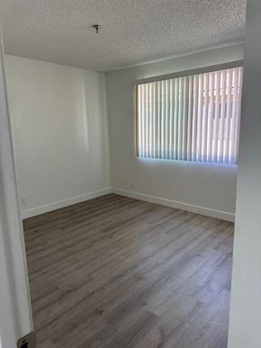 Santa Ana apartment for rent - A room with a window covered by blinds and wooden flooring.