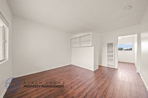 Hawthorne apartment for rent - A room with wooden floors and white walls, with a window on the left and a door on the right.